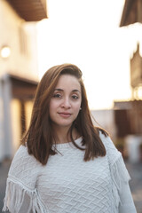 Caucasian woman with brown hair and white shirt on the beach at sunset.