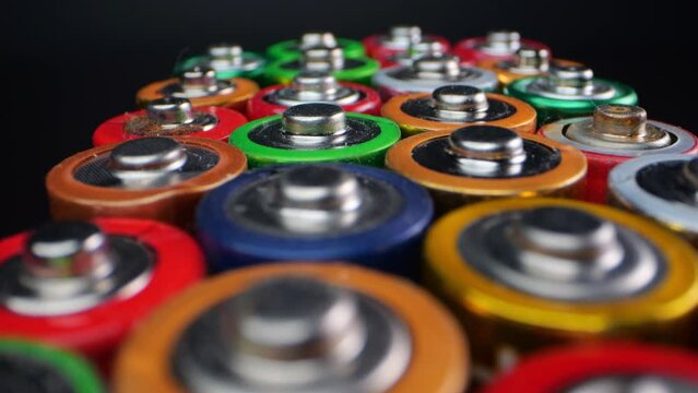 Macro view of old alkaline batteries, often used in portable audio players and digital cameras. Captured against a dark background.
