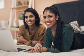 We always find something to keep us entertained online. two young women using a laptop while lying...