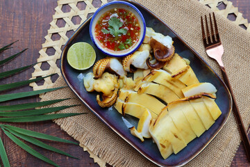 Charcoal grilled squid sliced serving with spicy seafood dipping sauce at top view - Thai famous seafood 