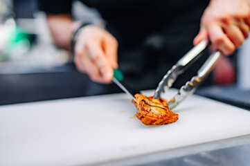 Obraz na płótnie Canvas chef is cutting chicken fillet in a restaurant kitchen
