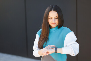 Woman uses a smart watch to measure the pulse on the hands. A woman does sports on the street....
