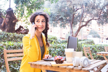 Woman talking on mobile sitting on a terrace of a cafeteria