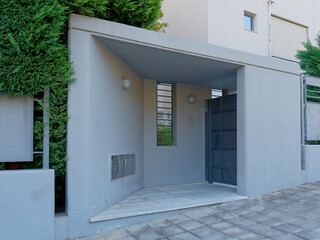 A modern house entrance metallic gray door by the sidewalk. Athens, Greece.