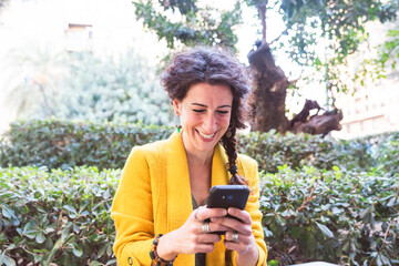 Woman looking at her phone with a cheerful appearance in a park