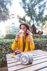 Woman drinking coffee sitting on a terrace with her mobile
