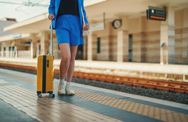 Woman with travel suitcase is waiting for a train.