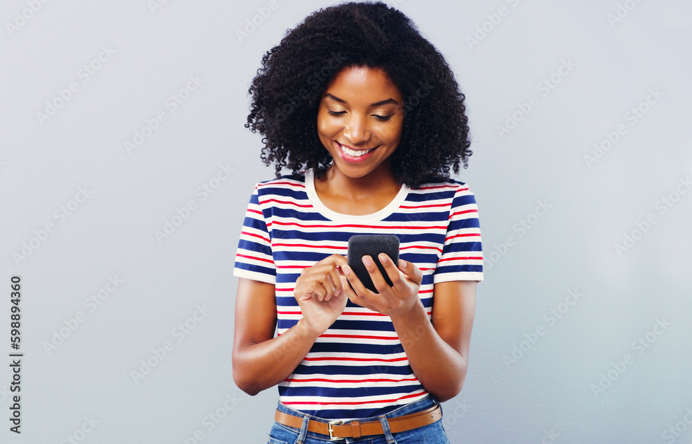 Poster Millennials live life in mobile form. Studio shot of a beautiful young woman using a smartphone against a grey background.