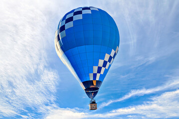 Blue hot air balloon flying on the blue sky with white clouds