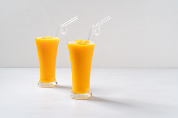 Fresh beautiful delicious mango juice smoothie in glass cup on gray table background.