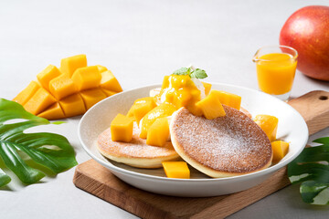 Delicious Japanese souffle pancake with dice mango and jam on gray table background.