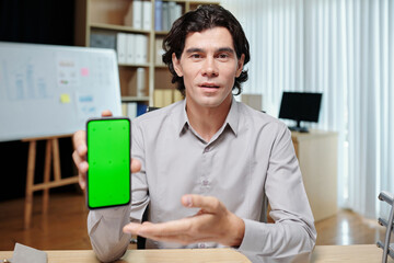 Developer showing smartphone with green screen when speaking in meeting with investors