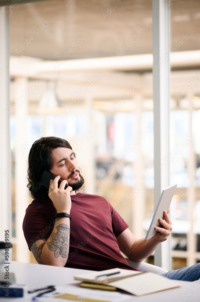 Poster im going to send you the updates right now. a young businessman talking on a cellphone while using a