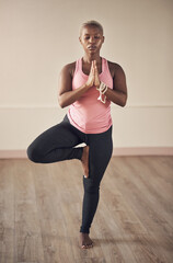 Control your thoughts before they control you. Full length shot of an attractive young woman holding a tree pose while doing yoga alone indoors.