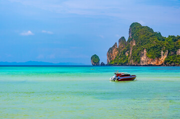Fototapeta na wymiar Landscape view of coastline with limestone rock and boats on ocean at Ko Phi Phi islands, Thailand. Concept of exotic tropical vacation and beautiful nature in paradise