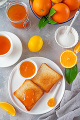 Toasts with orange marmalade or orange jam with cup of tea on a gray background. Delicious breakfast. Copy space.