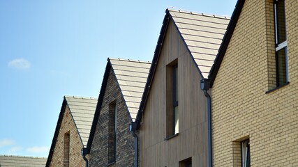Terraced family homes in newly developed housing estate. The real estate market in the suburbs. New single family houses in a new development area. Residential homes with modern facade. 