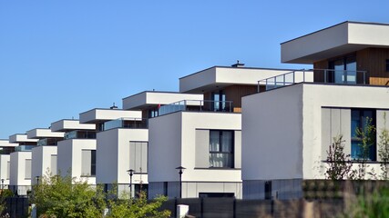 Terraced family homes in newly developed housing estate. The real estate market in the suburbs. New single family houses in a new development area. Residential homes with modern facade. 
