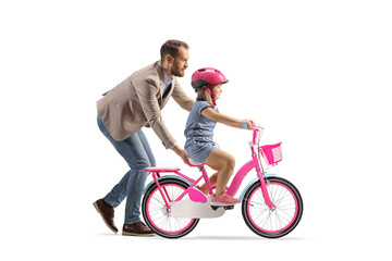 Profile shot of a father teaching a girl to ride a bicycle