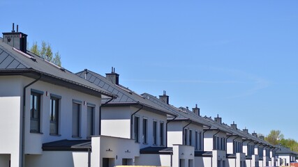 Terraced family homes in newly developed housing estate. The real estate market in the suburbs. New single family houses in a new development area. Residential homes with modern facade. 
