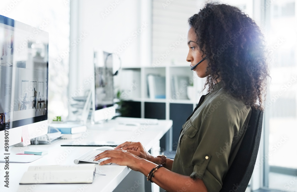 Poster focused on finding a solution. a young woman using a headset and computer in a modern office.
