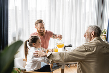 Positive same sex parents having breakfast with preteen daughter at home. 