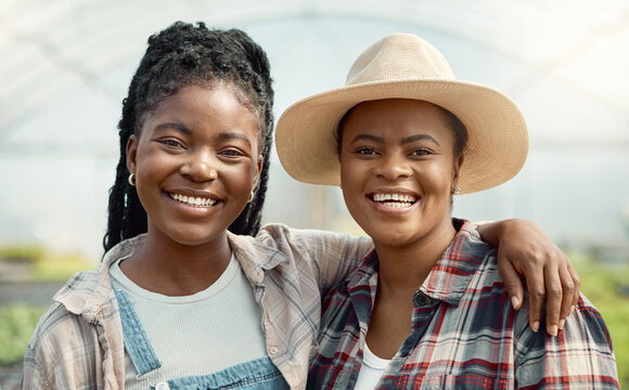 Faces of happy farm workers. Portrait of smiling colleagues in a greenhouse. African american farmers working in agriculture. Two women standing in their garden together. - Powered by Adobe