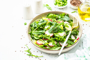 Green salad with spinach, arugula, radish with olive oil and seeds.