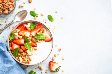 Healthy breakfast, Yogurt with granola, nuts and strawberries on white background. Top view with copy space.