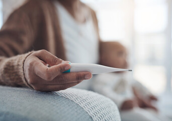 Nothing is worse than seeing your baby unwell. a woman checking her babys temperature with a thermometer on the sofa at home.