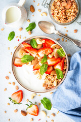 Yogurt with granola and strawberries on white. Healthy breakfast. Top view.