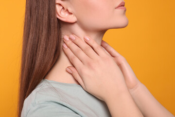 Obraz na płótnie Canvas Woman with sore throat on orange background, closeup