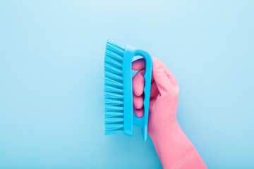 Cleaner hand in pink rubber protective glove holding and showing new cleaning brush on light blue...