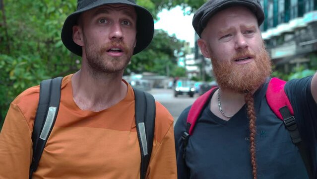 Caucasian tourist searching or looking for inexpensive hostels in Chiangmai downtown, groups of backpacker travel finding accommodation budget by walking in city, travelers using map after get lost
