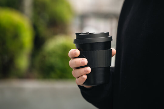 Reusable stylish bamboo black cup in the hands of a man, close-up, Eco friendly sustainable handy bamboo cup zero waste, no plastic concept. Generative AI