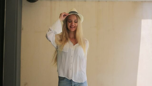 Summer Style Icon: A young woman with flowing blonde hair and a charming smile wears a white fedora hat and a casual white shirt, embodying effortless summer chic.