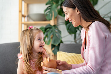 Portrait of a cute little girl with he mother holding piggy bank