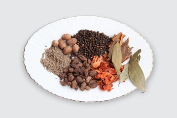 Indian garam masala ingredients in white plate dish and white background.