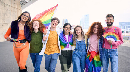 Group of young cheerful friends strolling together on day of gay pride parade in city. People LGBT community pose hugging looking smiling at camera outdoor. Generation z