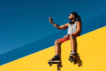 Black man listening music outside. Urban man posing with roller skates..