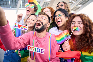 Diverse group of happy young people taking funny selfie for social media celebrating gay pride festival day. Lgbt community concept cheerful friends outdoors. Generation z enjoy party. - obrazy, fototapety, plakaty