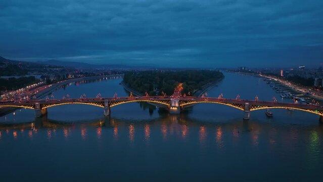 Aerial view of Budapest Margaret Bridge or Margit hid over the River Danube, embankment at night. Public transport in the city. Typical Yellow tram passing through the bridge