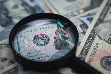 Stock market chart inside magnifier glass on Benjamin Franklin face of USD banknote for focus and...