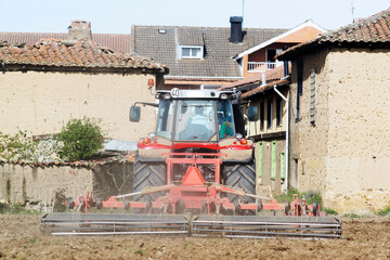 modern tractor cultivating the field at spring on old village of Spain