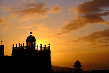 Fototapeta na wymiar Silhouette of building with old tower against sunset sky