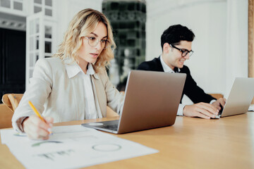 Female and male employees using laptops, colleagues in the office, teams of young people, creative managers, working on a startup together.