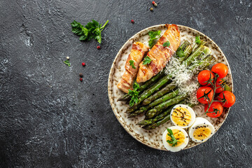 Baked chicken breast wrapped in bacon with asparagus, eggs and cherry tomato, Healthy fats, clean eating for weight loss. Keto paleo diet menu, top view