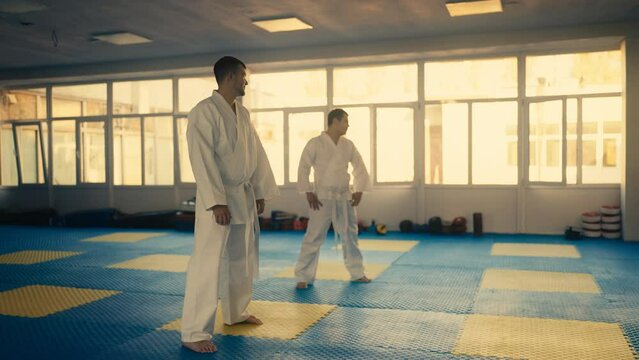 Men in white kimonos warming up before training, martial art school, sparring