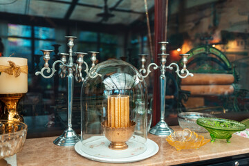 Vintage candle holder on wooden table with glassware. Stylish cafe or antique exhibition