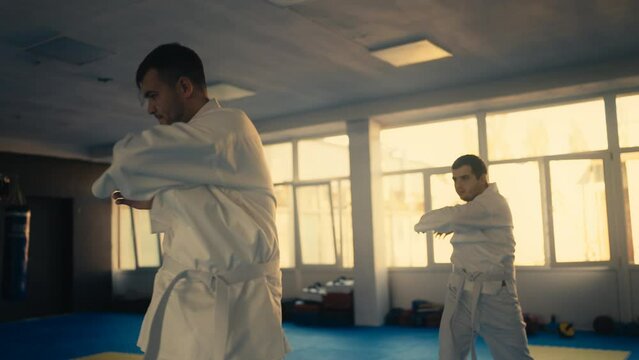 Two men warming up before taekwondo training, master and student in gym